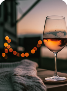 Couple by lake at The Regatta on Grand luxury RV resort, with a glass of wine by a fire.